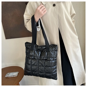 Close-up of black quilted puffer tote bag made of glossy nylon with high-capacity design