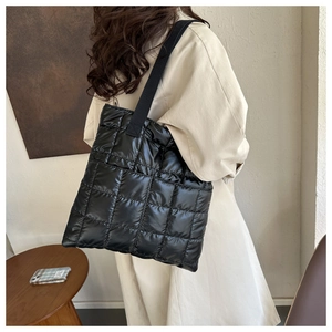 Detail of black quilted down tote bag showing puffy nylon fabric and shoulder strap