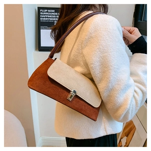 Detail of color-block underarm bag with suede texture and metal clasp on shoulder