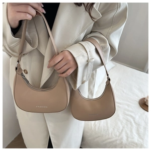 Close-up of beige crescent underarm bags in two sizes with fashion logo and leather texture