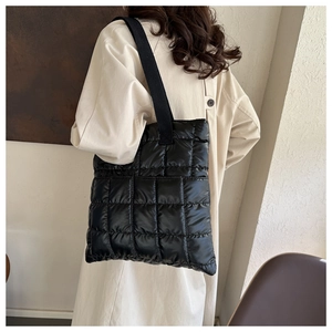Detailed view of black quilted down tote bag showing puffy texture and soft fabric shoulder strap