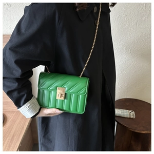 Close-up of green quilted faux leather crossbody bag with golden chain and metal lock