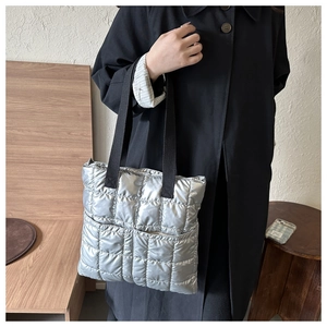 Detail of silver quilted bucket bag with grid pattern and black fabric straps