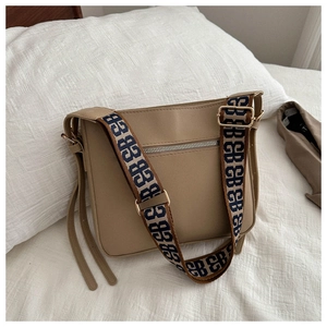 Dettaglio borsa in pelle kaki con ampia tracolla in jacquard a motivi e cerniera in metallo