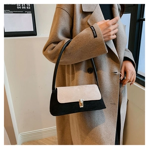 Detail shot of a two-tone suede underarm bag with an elegant golden rotating metal lock