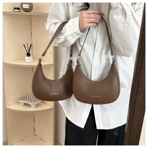 Detail shot of brown faux leather half-moon bag featuring silver Fashion logo and adjustable strap