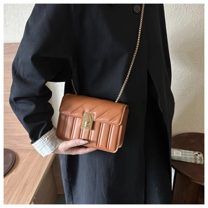 Detailed view of the brown leather crossbody bag with V-shaped stitching and gold chain