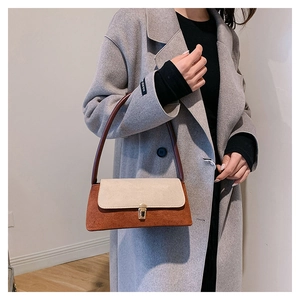 Minimalist colorblock suede shoulder bag with gold square buckle shown on grey coat
