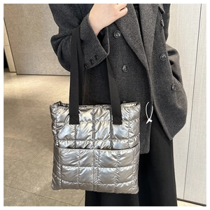 Macro shot of silver quilted puffer tote bag with metallic sheen and black straps