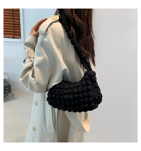 Detail of black cloud puff shoulder bag featuring popcorn texture on a beige coat