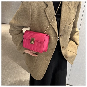 Detail of fuchsia quilted chain crossbody bag with luxury gold lock on model