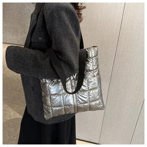 Close-up detail of quilted metallic silver down tote bag with wide black strap
