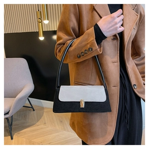 Detail of color-block underarm bag featuring a matte grey flap and gold metal lock