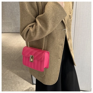 Hot pink quilted chain crossbody bag shown with a brown wool blazer in lifestyle view
