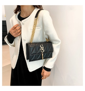 Detail of black quilted shoulder bag featuring gold SS logo, fringe, and metal chain