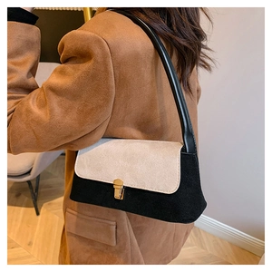 Detail of contrast color crossbody bag with gold buckle on a model in a brown coat