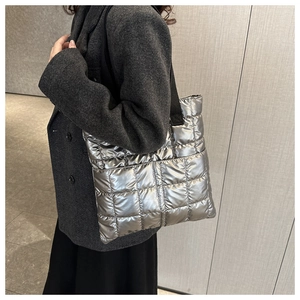 Close-up of shiny silver quilted tote bag featuring metallic finish and black nylon strap