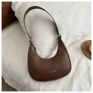Close-up of dark brown leather crescent shoulder bag with silver Fashion text on fabric
