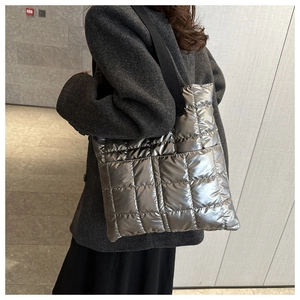 Detail of silver quilted puffer tote bag with metallic finish and wide black shoulder strap