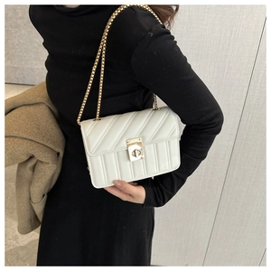 Close-up of white quilted chain crossbody bag with golden rectangular turn-lock buckle
