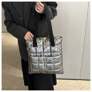 Detail of silver quilted puffer tote with black webbing straps and metallic snap button