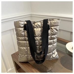 Detailed quilted champagne gold puffer tote bag with metallic texture on wooden surface