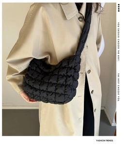 Detail of black quilted puffer bag with crossbody padded strap and soft texture