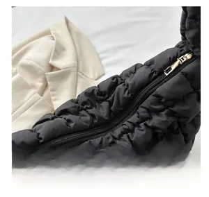 Detail of golden metal zipper and black quilted nylon fabric on cloud crossbody bag