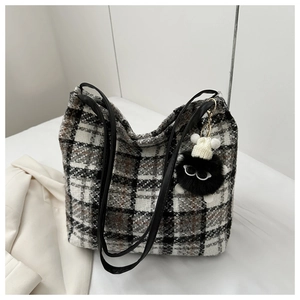 Detailaufnahme der Tweed-Einkaufstasche mit Karomuster, Lederriemen und Plüschanhänger