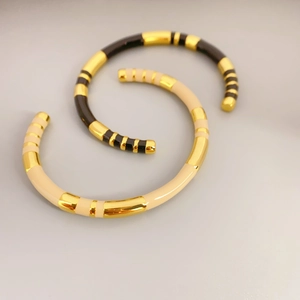 Detailed view of bamboo style enamel bangles with gold stripes in beige and black