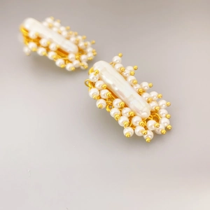 Vintage gold stud earrings featuring a long baroque pearl and small pearl clusters