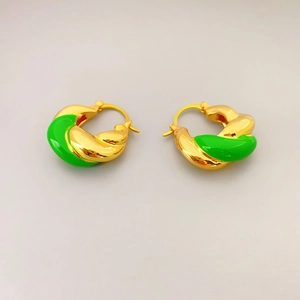 Close-up of gold-plated croissant hoop earrings with vibrant green enamel finish