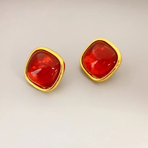 Close-up of vintage square stud earrings with red gemstones and gold-plated metal edges