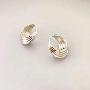 Elegant silver layered ribbed hoop earrings with a textured curved structure and snap closure