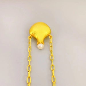 Detail of a gold-plated perfume bottle pendant featuring a round white cultured pearl