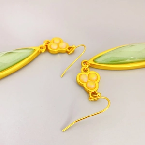 Elegant gold drop earrings featuring pale green teardrop stones and floral bead accents