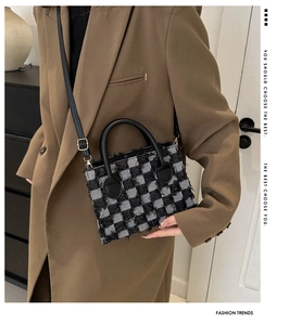 Detail of checkered crossbody bag with fringe trim worn over a brown blazer