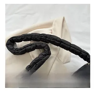 Detail of wide padded shoulder strap on a black quilted puffy nylon cloud bag
