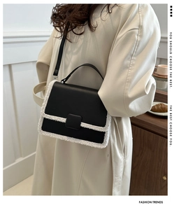 Detail of black leather crossbody bag with white faux shearling trim and top handle
