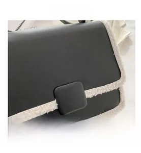 Detail of black leather shoulder bag with white faux shearling trim and square buckle