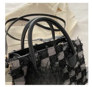 Detailed close-up of plaid fabric texture and leather handle on a vintage denim tote bag