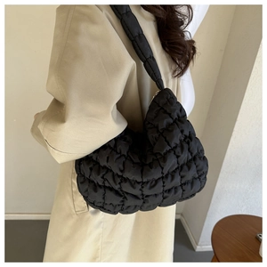 Detail of black quilted cloud bag showing the puffy nylon texture and wide shoulder strap