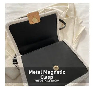 Detail of the magnetic snap closure on a black and white contrast shoulder bag