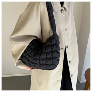 Detail of black quilted cloud bag texture and appearance on beige trench coat