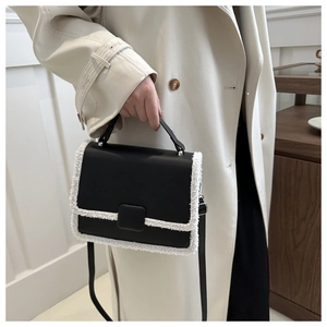 Close-up of black PU leather bag with white sherpa trim and adjustable shoulder strap