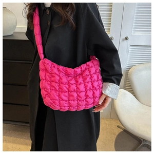 Detail view of red quilted puffer shoulder bag showing soft padded texture on black coat