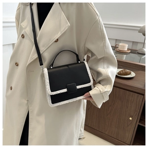 Detail of a chic black leather crossbody bag with white faux fur trim and gold-tone clasp