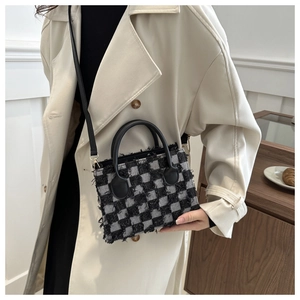 Detail of checkerboard mini bag with fringe edges on a classic beige trench coat