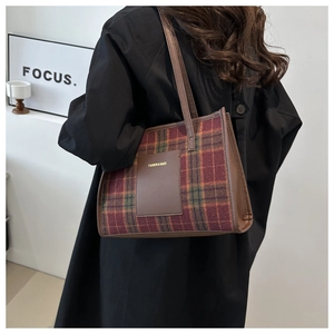 Detalle del bolso tote de lana a cuadros con diseño rojo y marrón y correas de cuero