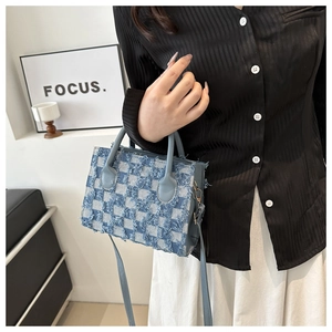 Detail of blue denim checkered handbag with fringe edges and detachable shoulder strap